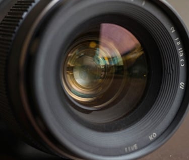 An extreme close up of a lens reflecting charcoal gray and antique gold light, cinematic depth of field, sophisticated and artistic style.