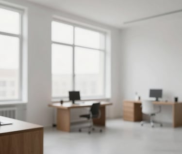 Interior shot of a minimalist design studio with large windows. The palette features #FBF9F6 walls and #6B6760 furniture. Clean, bright, and modern atmosphere representing professional elegance.
