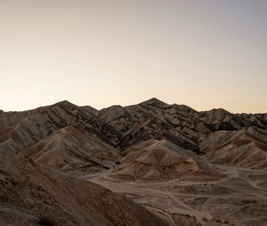 Landscape photography of a desert ridge at dusk in Northeast Nevada. The sky is a gradient of off-white and sand beige. The silhouette of the ridge is sharp, conveying the rugged beauty and immense potential of the land.