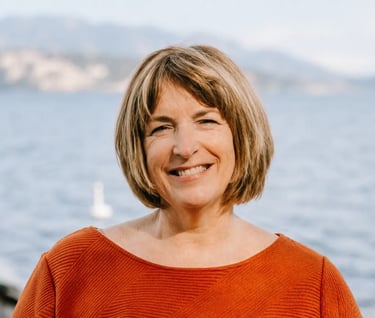 a senior short blonde hair lady, named Susan Noble, with okanagan lake on her back