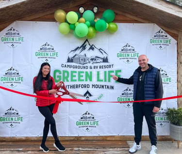 A couple celebrates the grand opening of Green Life Campground & RV Resort with a ribbon cutting ceremony.
