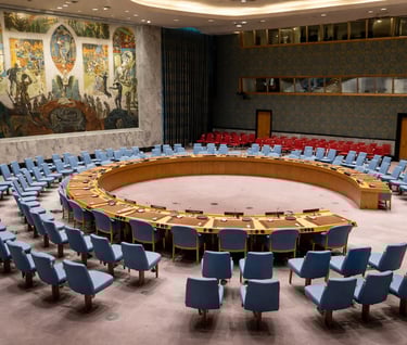 Sala de consejo internacional con mesa circular y asientos dispuestos para deliberación multilateral