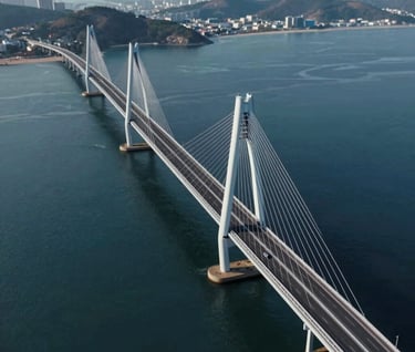 Cinematic drone view of a sleek, modern bridge stretching across a deep blue bay. Symmetrical composition, featuring cool tones of #415A77 and metallic highlights of #A0B0C0. High-end video production quality.
