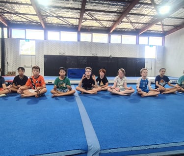 a group of children sitting on a blue mat
