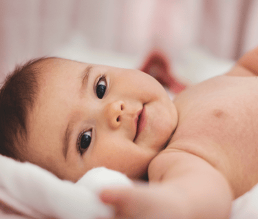 a baby laying and smiling.
