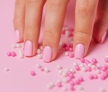 a hand with pink nail paint and some pearls