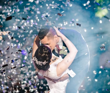 a bride and groom kissing in front of confettittittittittitti