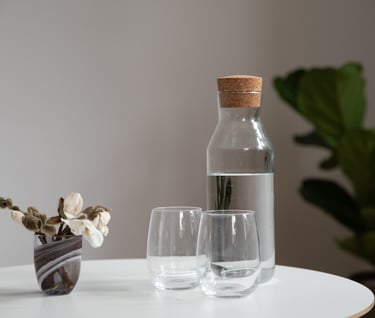 En kande med vand på et blomsterdækket bord