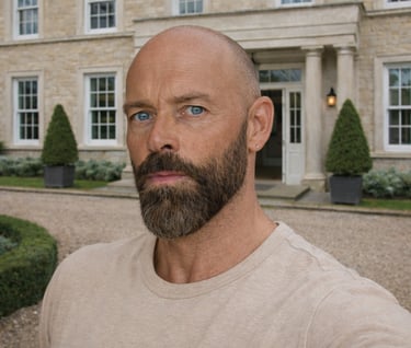 Portrait of Damon with a beard standing in front of a luxury limestone manor house.