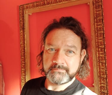 The writer Ian Farnes, framed by a gold picture frame on a red background. he looks at the camera