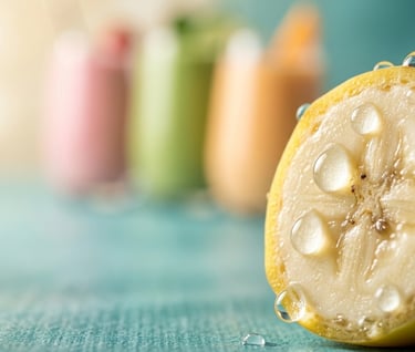 Fresh banana slice with water droplets and blurred fruit smoothies on a turquoise background.