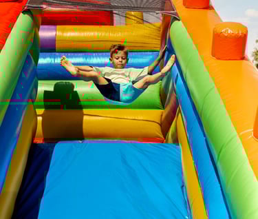 a boy is playing on a slider in a bouncer