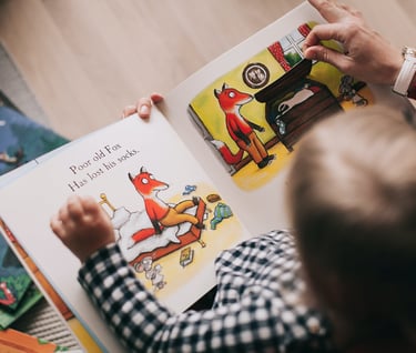 a child's hands are holding a book, the child is learning reading