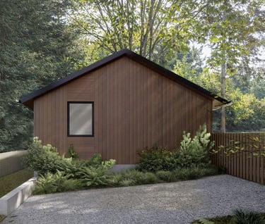 Modern wood-sided cabin with a gable roof nestled in a lush green forest setting.