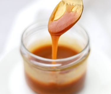 cuchara con dulce de leche en vaso de vidrio