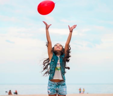 Little girl playing and trying to reach a red balloon