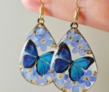 a pair of blue butterflies in a tear shaped glass earrings