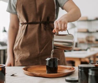 a person in a apron is pouring coffee into a cup