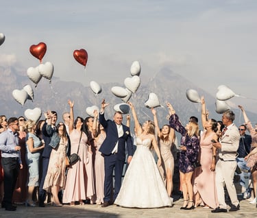 Grupowe zdjęcie pary młodej z gośćmi trzymającymi balony