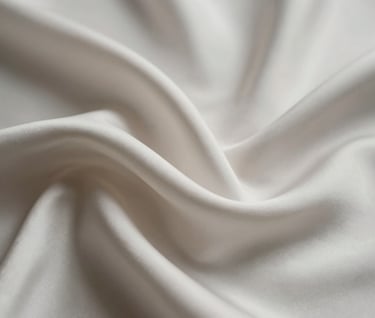 An artistic close-up of fine silk fabric flowing gracefully in motion, creating abstract shapes. The lighting is subtle, highlighting textures in a palette of #6B625E and #F5F4F0. The overall mood is one of creative, professional elegance.