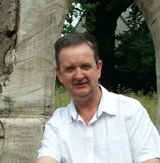Bruce Clifton sitting in front of a memorial to the oldest trees in Cumbria, UK