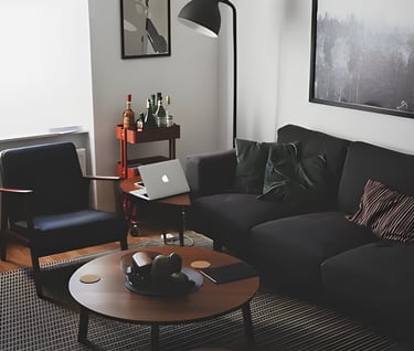 Modern living room with black leather sofa and laptop, illustrating accommodation options forstudent