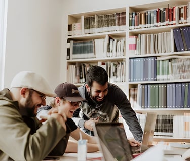 Three men in a library engaged in a discussion about studying abroad