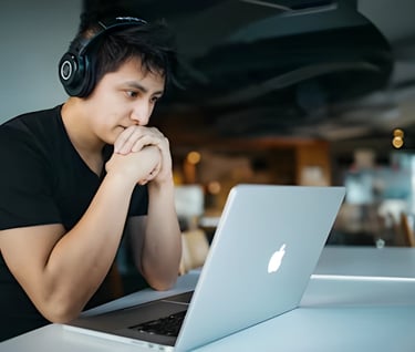 Student focusing on SAT prep with laptop and headphones, highlighting Admit 360's online SAT test 