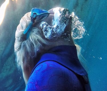Woman snorkeling to the surface with goggles and air buccle on her face