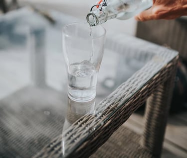 a person pouring water into a glass of water