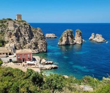 Panoramic view of Tonnara di Scopello featuring coastal rock stacks and the historic tower in Sicily.