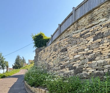 Curved retaining wall built using Cotswold stone in a rustic style