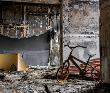 Estancia de una vivienda después de un incendio, se ve bicicleta quemada, paredes y muebles quemados