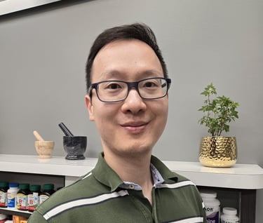 A man with short black hair, glasses and green shirt