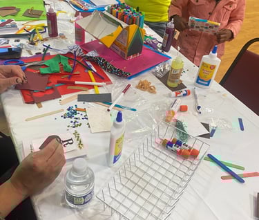 a group of people sitting at a table with craft supplies making a creative journal
