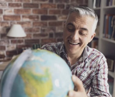 Homem sorridente segurando globo terrestre, representando expatriados e mobilidade global.