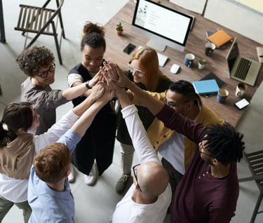 A group of people in an office, hands raised, ready to assist.