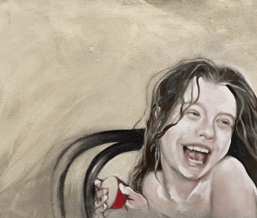 Head and shoulders of a young girl with long hair sitting on a chair laughing, holding an apple.