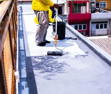 a man in a yellow jacket is painting a roof