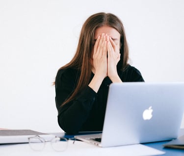 a woman sitting at a desk with her hands covering her face