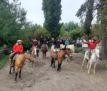 A group of people on horseback smiling and waving.