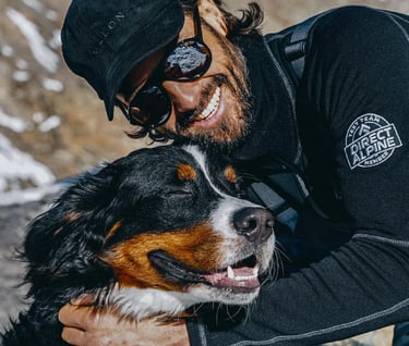 a man in a black jacket and sunglasses is holding a dog