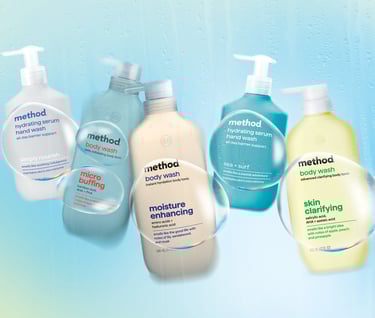 An assortment of Method body wash and hydrating hand wash bottles behind a condensation-covered glass.
