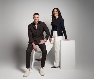 Professional studio portrait of a man and woman in business casual attire posing against a grey backdrop.