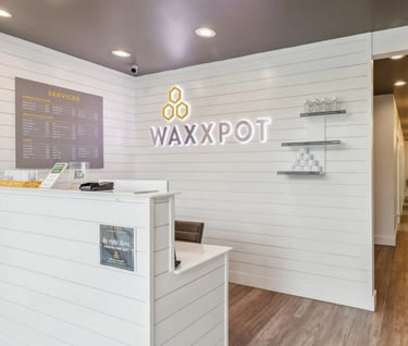 a white reception desk with a white counter top and a neon sign that says wax