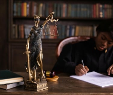 Judge sitting at a desk with a figure of blind justice holding the scales of justice.
