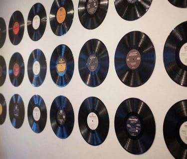 A collection of custom vinyl records displayed in a gallery-style layout in a North American / US creative space, featuring monochromatic navy artwork.