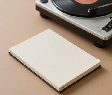 Minimalist photograph of a hardbound journal sitting next to a modern record player on a tan surface. Soft shadows and a clean composition reflecting a quiet moment of writing and listening. International / Western home office setting.