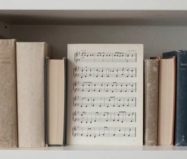 A collection of scholarly books and music scores neatly arranged on a minimalist shelf, representing musical research. Refined and intellectual atmosphere. Soft off-white and muted stone brown palette. Southern European / Spanish university library feel.