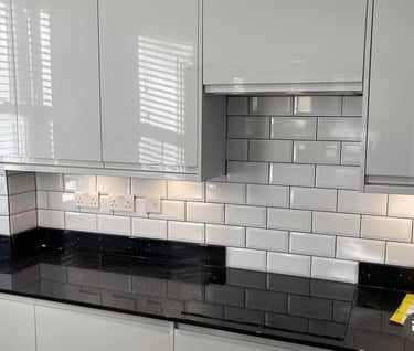 Modern white gloss kitchen cabinets with white subway tile backsplash and black granite countertops.